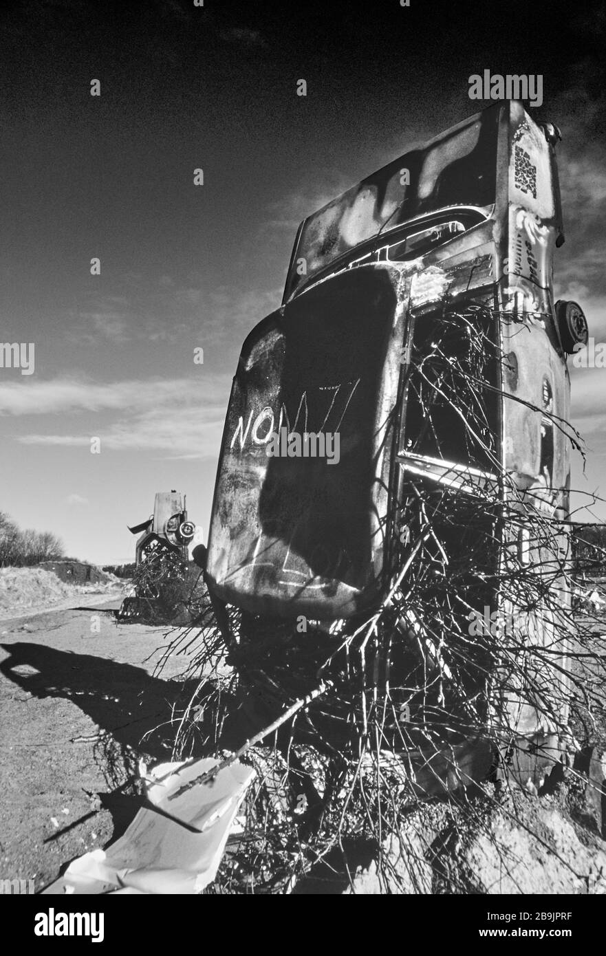 Carhenge a Pollock Park, Glasgow 1994. Una collezione di auto arrugginite rovesciate e coperte di graffiti come protesta per la costruzione dell'autostrada M77. Foto Stock