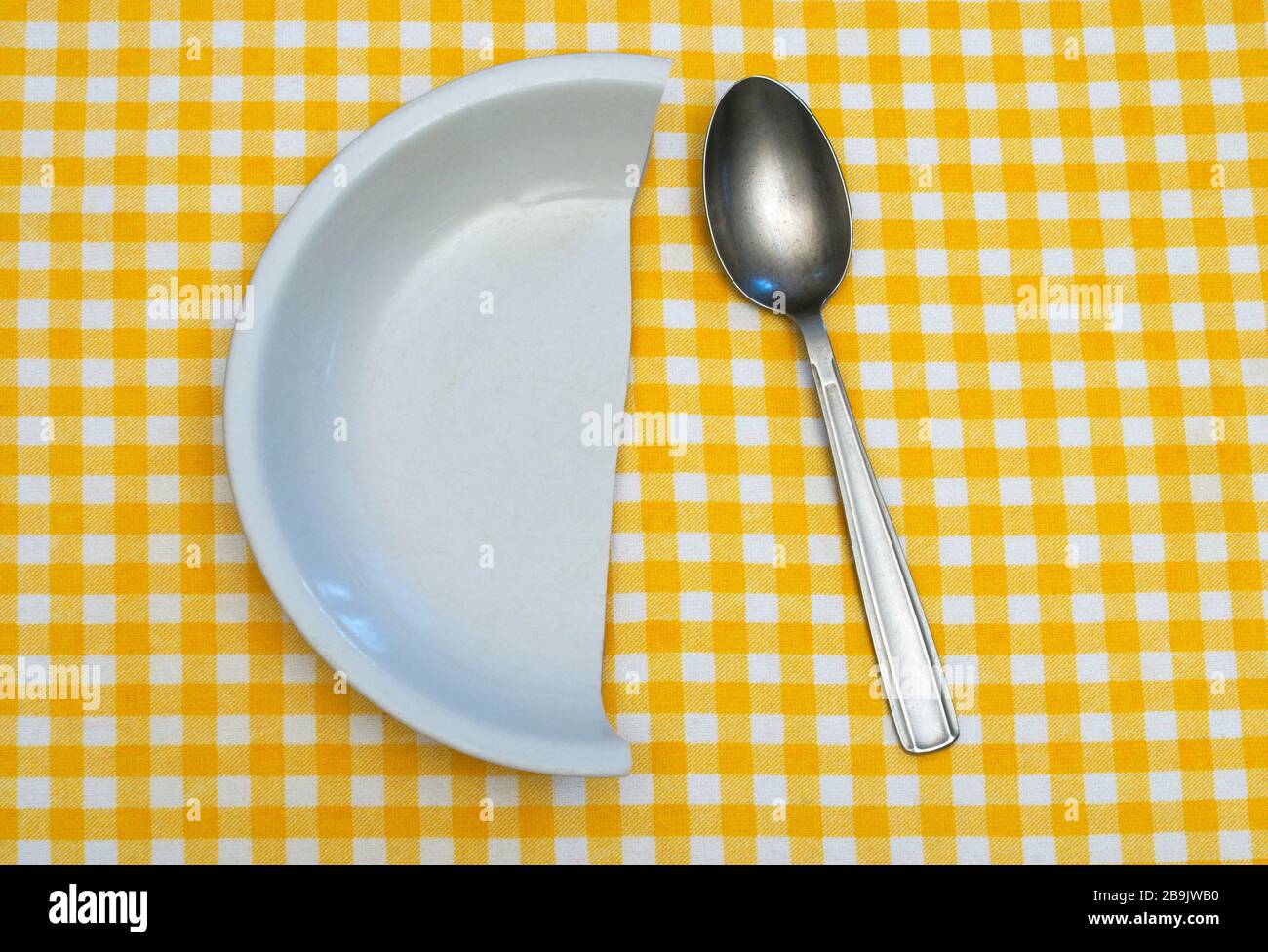 cucchiaio e mezza piastra sulla tovaglia a scacchi Foto Stock