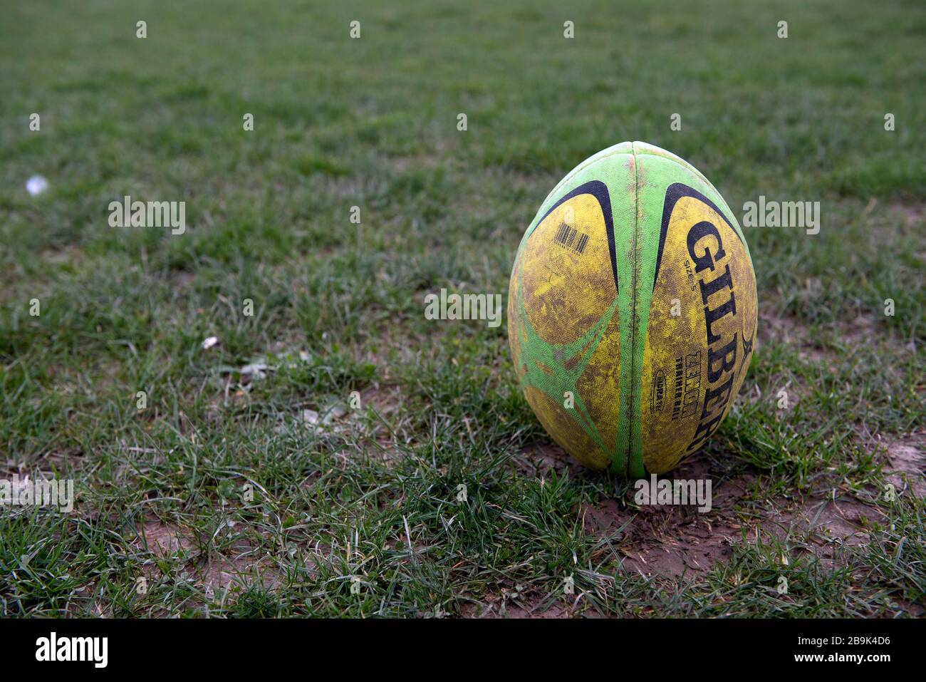 Una palla di rugby Gilbert used sporca di dimensioni normali è posta alla  fine in un campo fangoso in attesa di essere calciato all'inizio di una  partita o per la conversione dopo