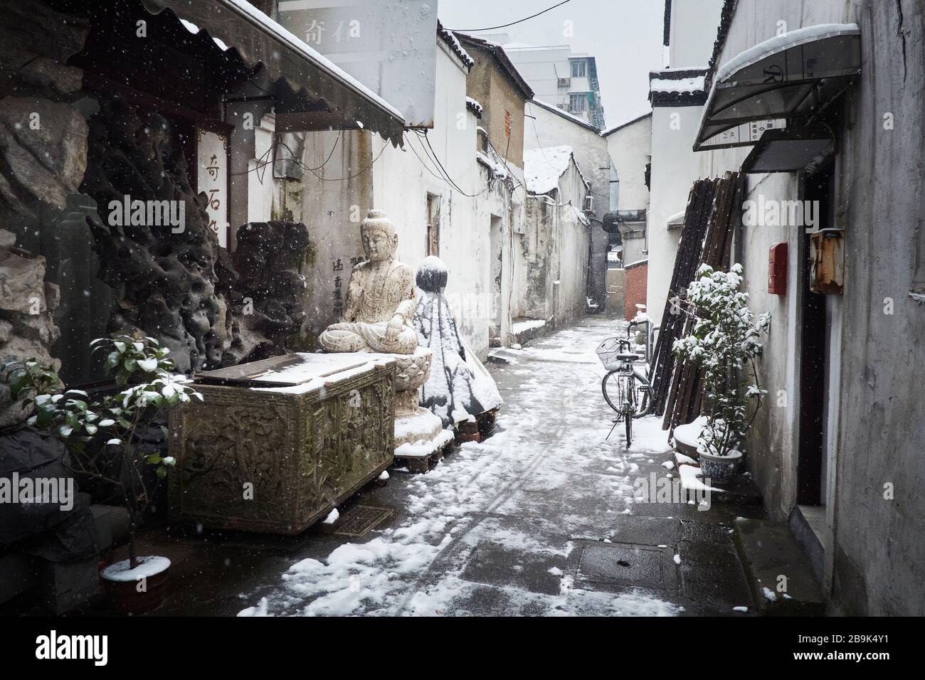 Una scena di strada innevata nella città cinese di Hangzhou, che mostra un Buddha e una bicicletta. Foto Stock