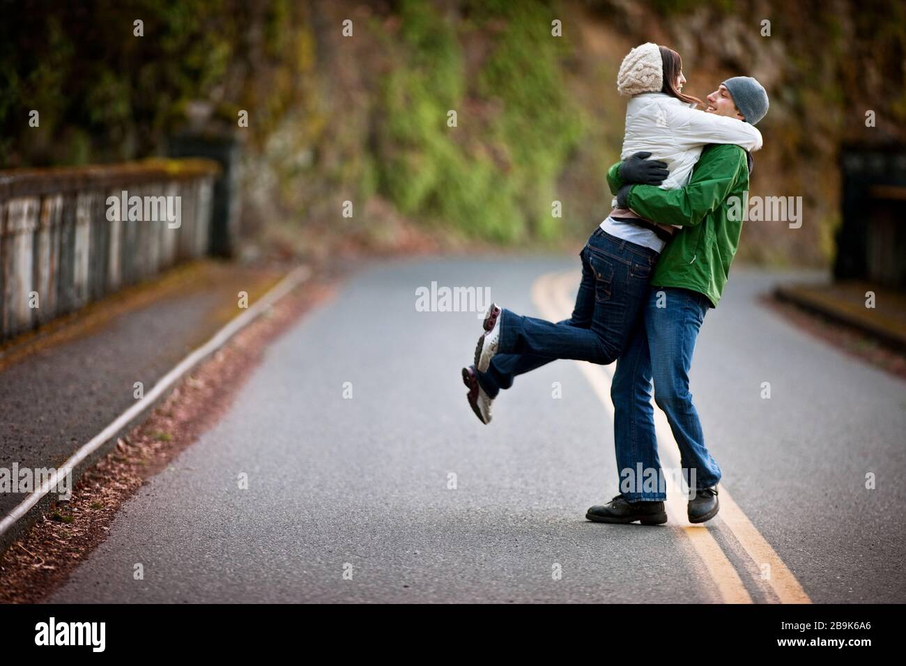 Uomo che solleva la donna in aria sulla strada Foto Stock