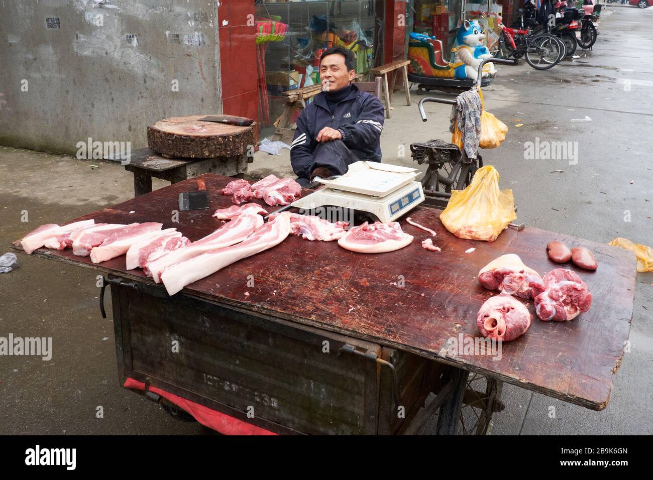 Un macellaio che vende carne sulla strada nella città cinese di Huangshi Foto Stock