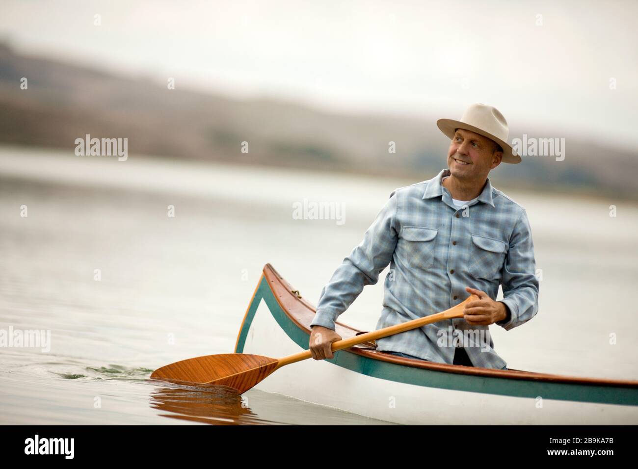 L'uomo canoa in acque calme. Foto Stock