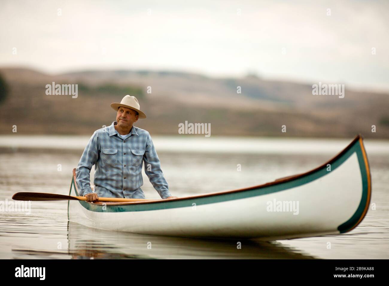 L'uomo canoa in acque calme. Foto Stock