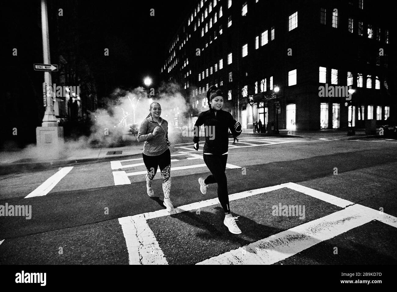 Due donne corrono di notte di fronte a Boston. Foto Stock