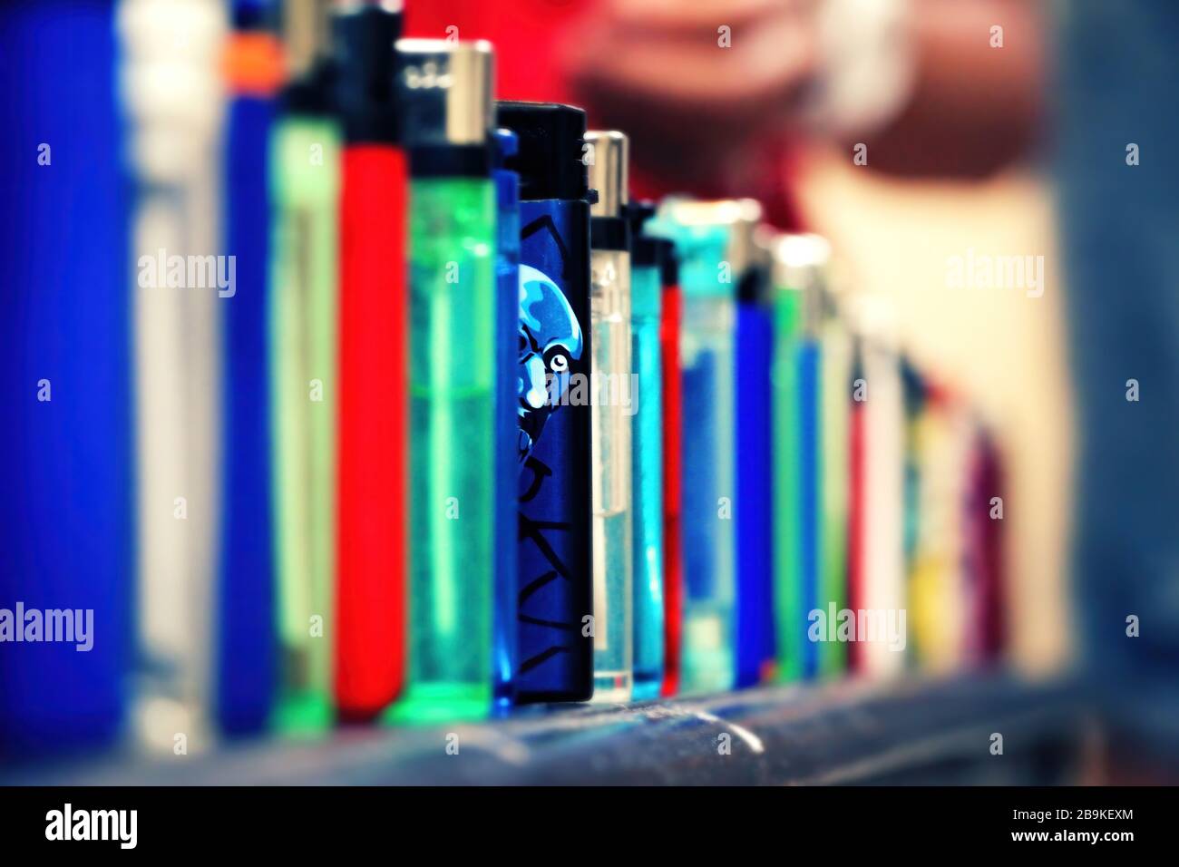 Accendini allineati. Un accendino di colore blu si distingue dal resto. Il volto dell'uomo è illustrato su di esso e sembra che sguardi fuori alla macchina fotografica. Chiudi Foto Stock