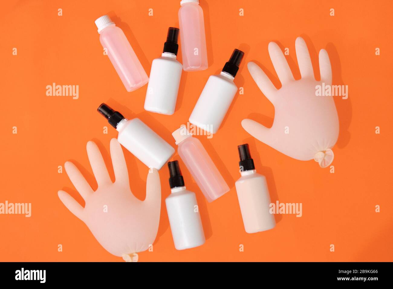 Igienizzante per mani a base di alcol, guanti su fondo arancione. Foto Stock