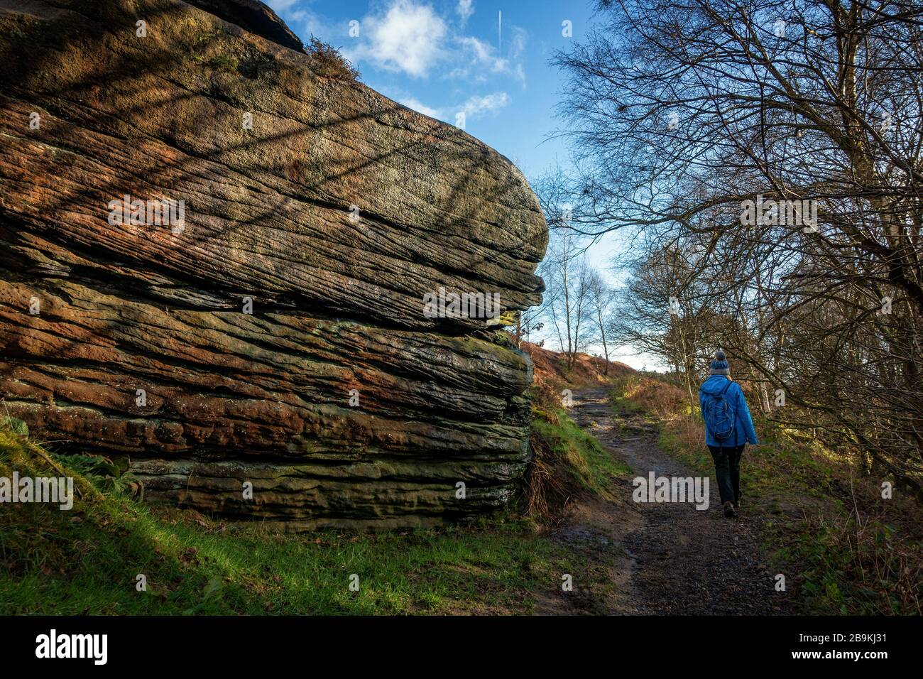 Persona che si gode una passeggiata invernale a Shipley Glen con massi enormi in bella luce, West Yorkshire, Inghilterra, Regno Unito Foto Stock