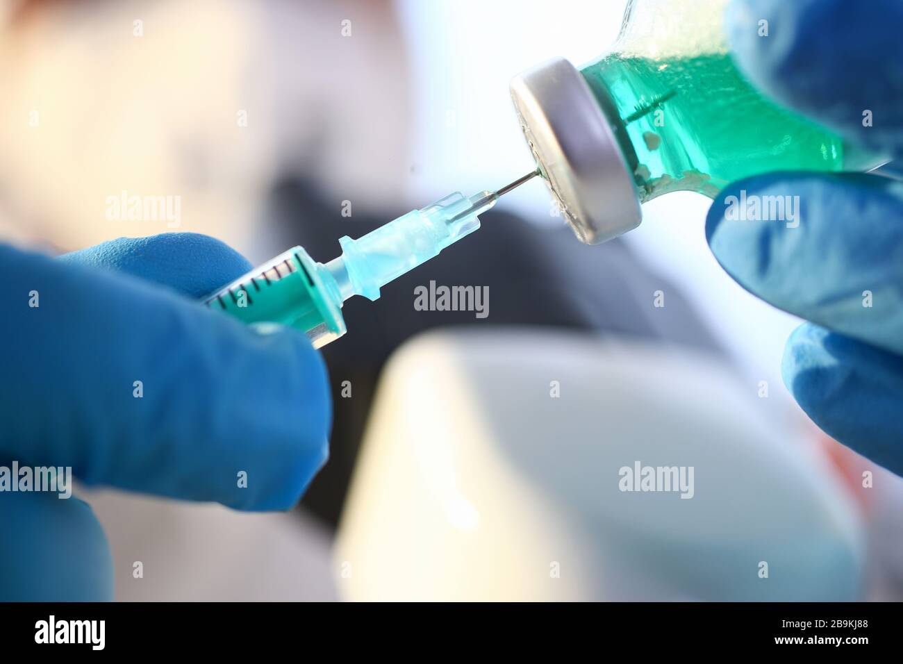 Gli scienziati indossano guanti protettivi blu riempiendo la siringa con un po' di liquido sperimentale Foto Stock