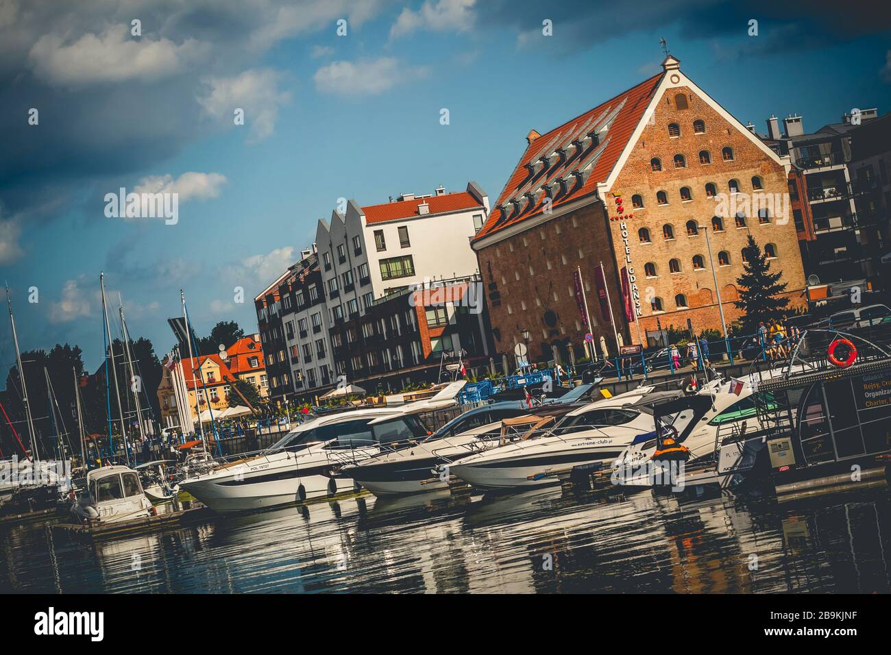 Yacht moderni ormeggiati in porto turistico Gdansk sul fiume New Motlawa a Gdansk, Polonia con vecchi edifici sullo sfondo Foto Stock