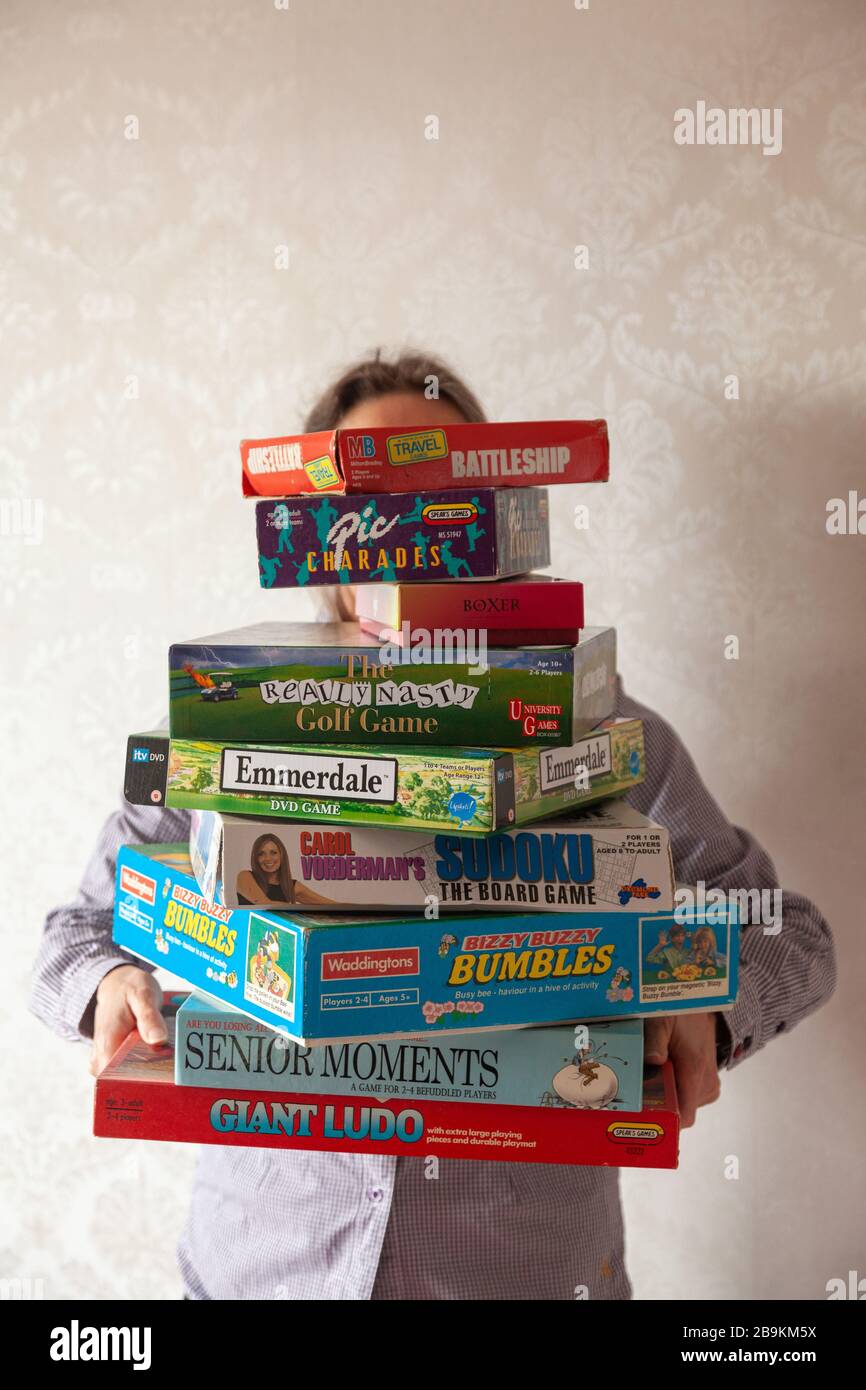Una persona che detiene una grande collezione di giochi da tavolo Foto Stock