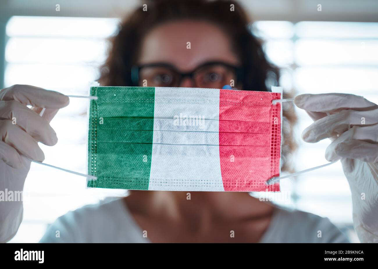 Coronavirus pandemico. Primo piano di giovane donna con maschera chirurgica con la bandiera d'italia su di essa Foto Stock