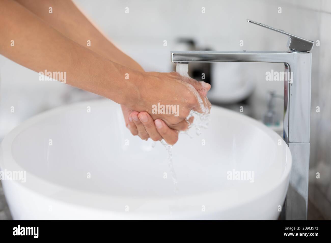Acqua versare dal rubinetto mentre donna lavare le mani vista primo piano Foto Stock