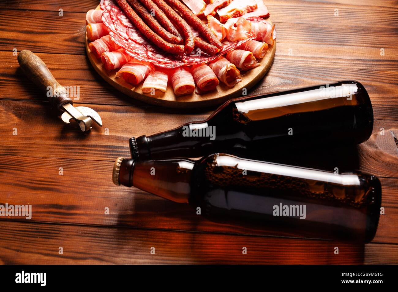 Snack di birra sotto forma di prodotti a base di carne e birra in bottiglia. Antipasto in forma di pancetta affettata, salame, prosciutto, salsicce di caccia. Scorta foto birra e. Foto Stock