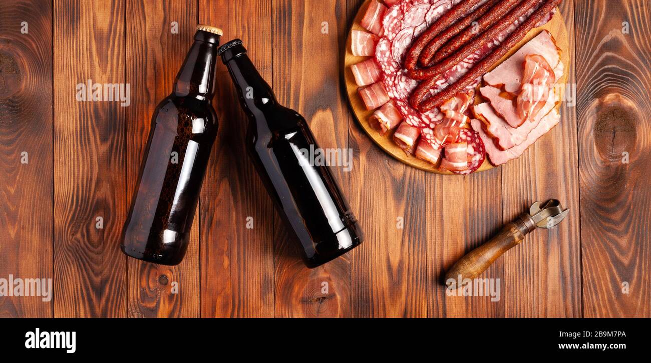 Snack di birra sotto forma di prodotti a base di carne e birra in bottiglia. Antipasto in forma di pancetta affettata, salame, prosciutto, salsicce di caccia. Scorta foto birra e. Foto Stock