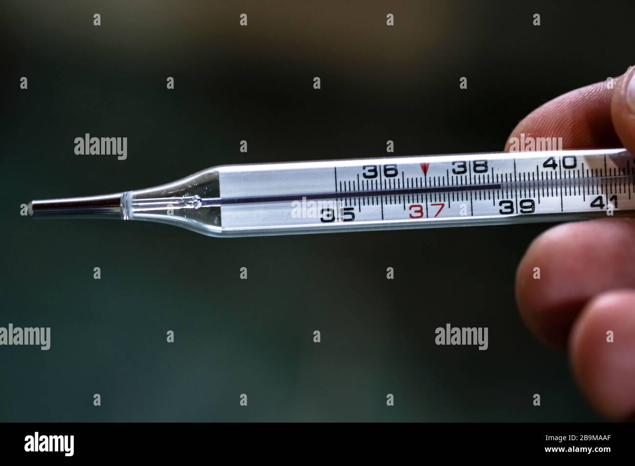 L'uomo ha un termometro con febbre da mercurio dopo la misurazione, co-caviri19 Foto Stock