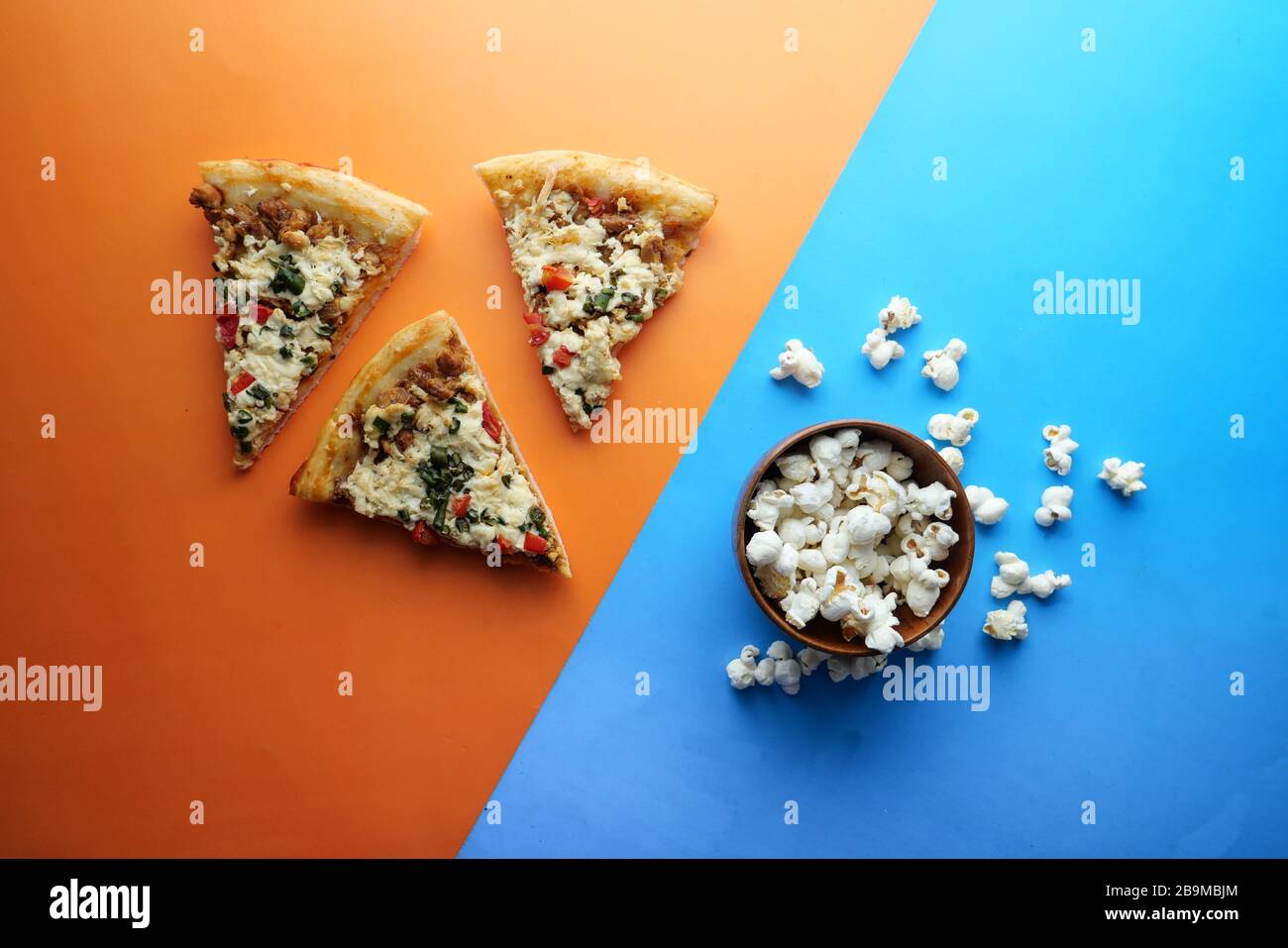vista dall'alto della pizza, popcorn su sfondo colorato. Foto Stock