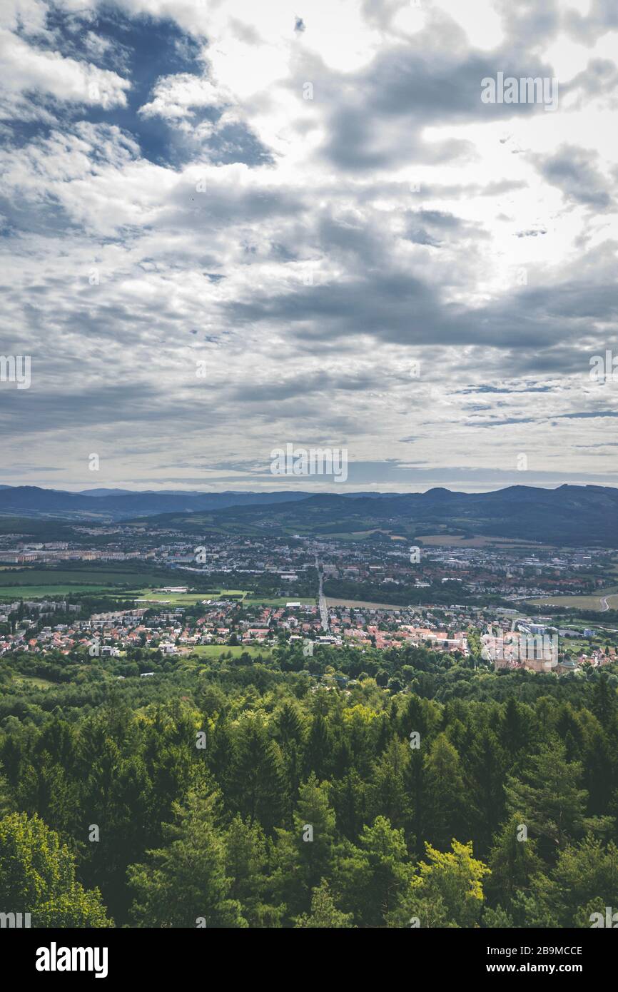 Vista panoramica grandangolare dal punto di osservazione sopra la città con alberi e colline in giornata nuvolosa Foto Stock
