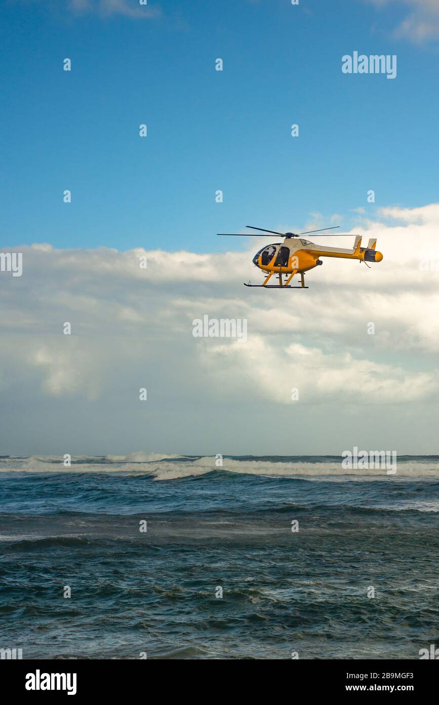 Un elicottero si aggira sopra il Rough Seas al largo della costa delle Hawaii Foto Stock