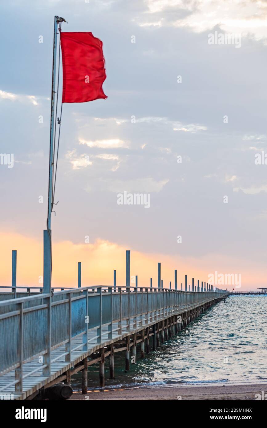 Bandiera rossa che vola sul ponte del pontone, avvertimento del vento e delle onde in aumento. Mar Rosso, Egitto Foto Stock