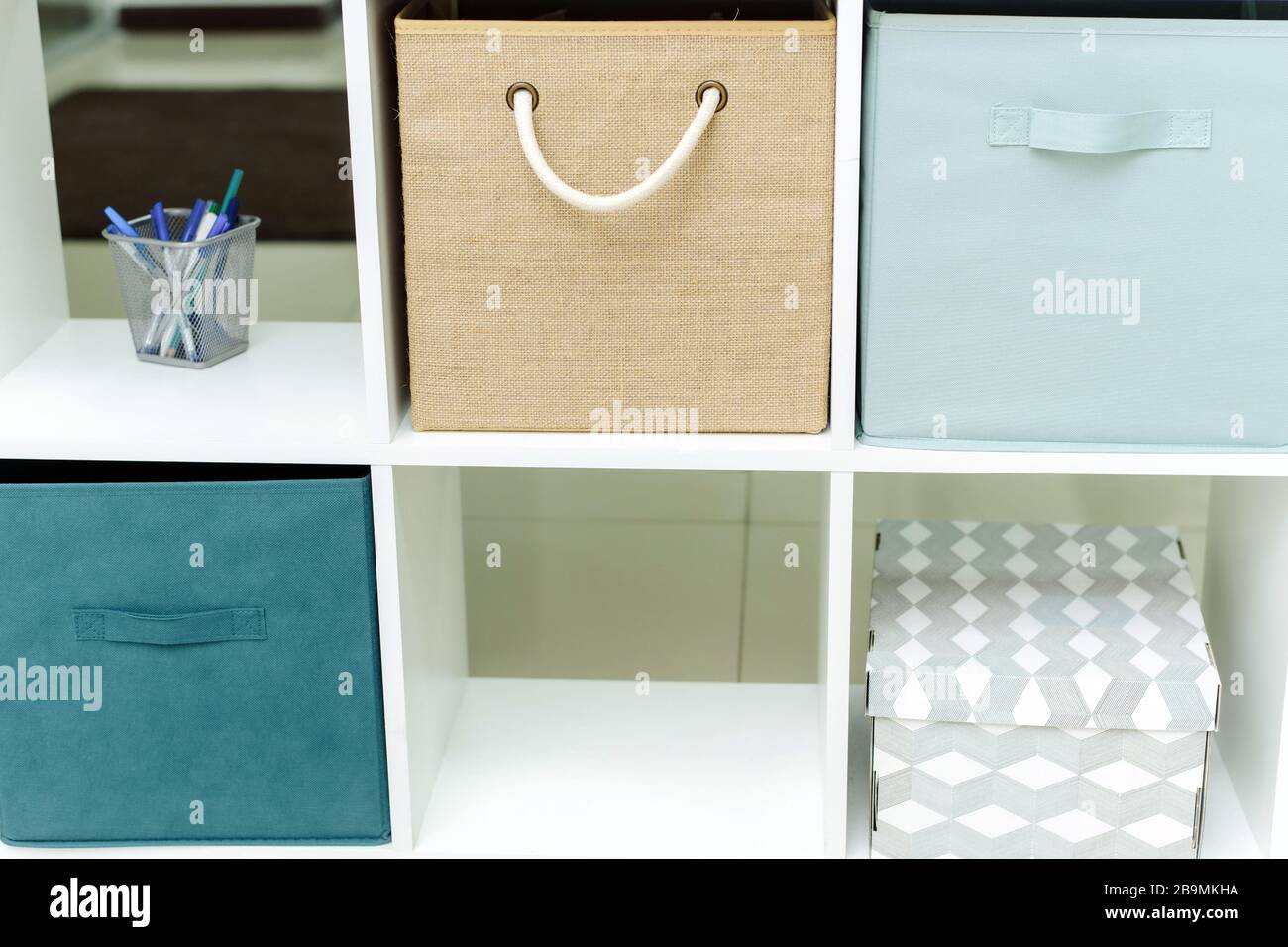 Scatole e organizer in un armadietto bianco per ufficio. Ufficio luminoso in toni blu e beige. Foto Stock