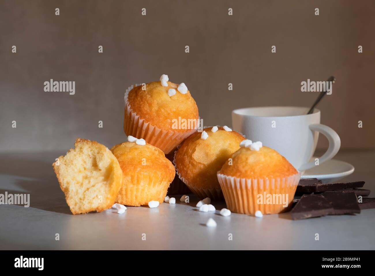 Muffin con zucchero perlato, una tazza di caffè e pezzi di cioccolato Foto Stock
