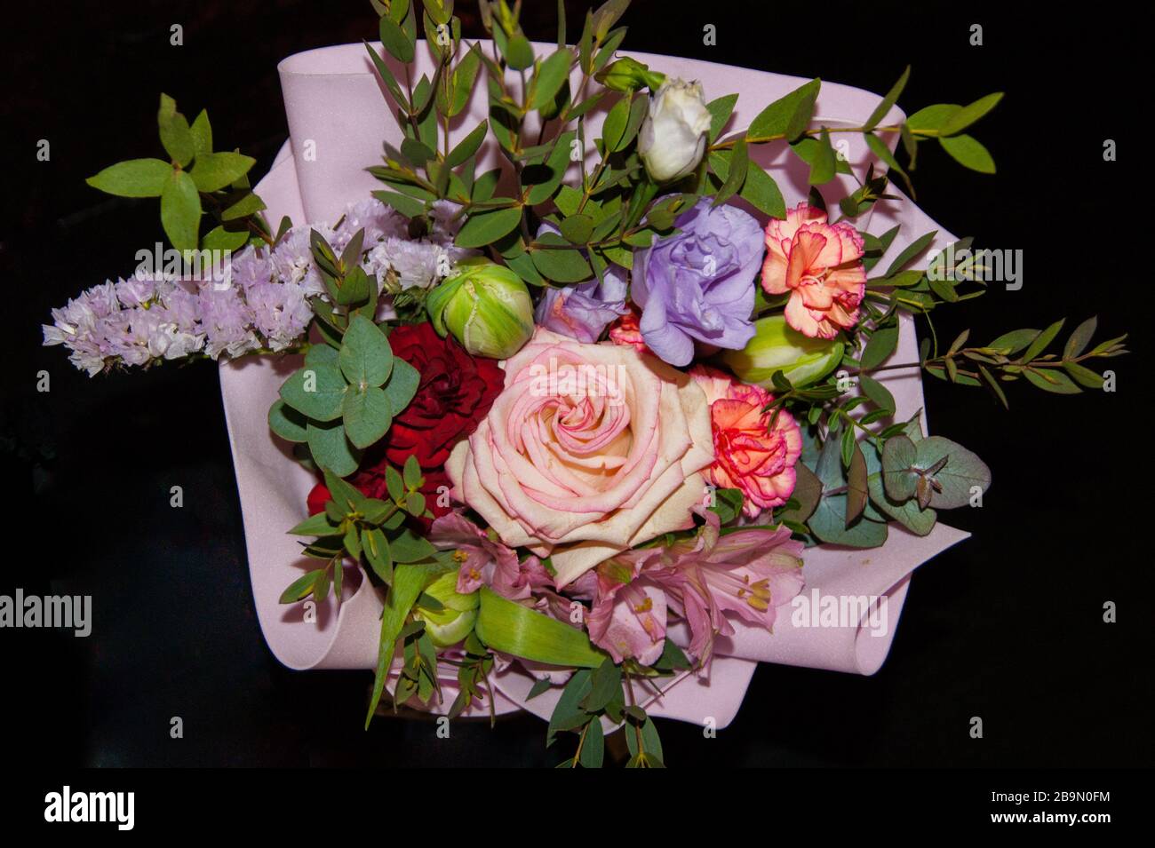 Delicato bouquet di fiori diversi in confezione rosa. Foto orizzontale ravvicinata. Foto Stock