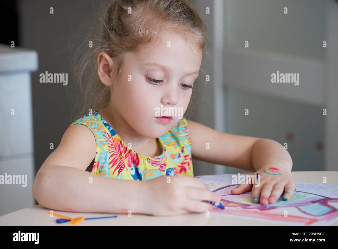 Creatività dei bambini. Bambina piccola disegna con matite di cera a casa. Il concetto di apprendimento a distanza on-line per il periodo di quarantena globale. Foto Stock