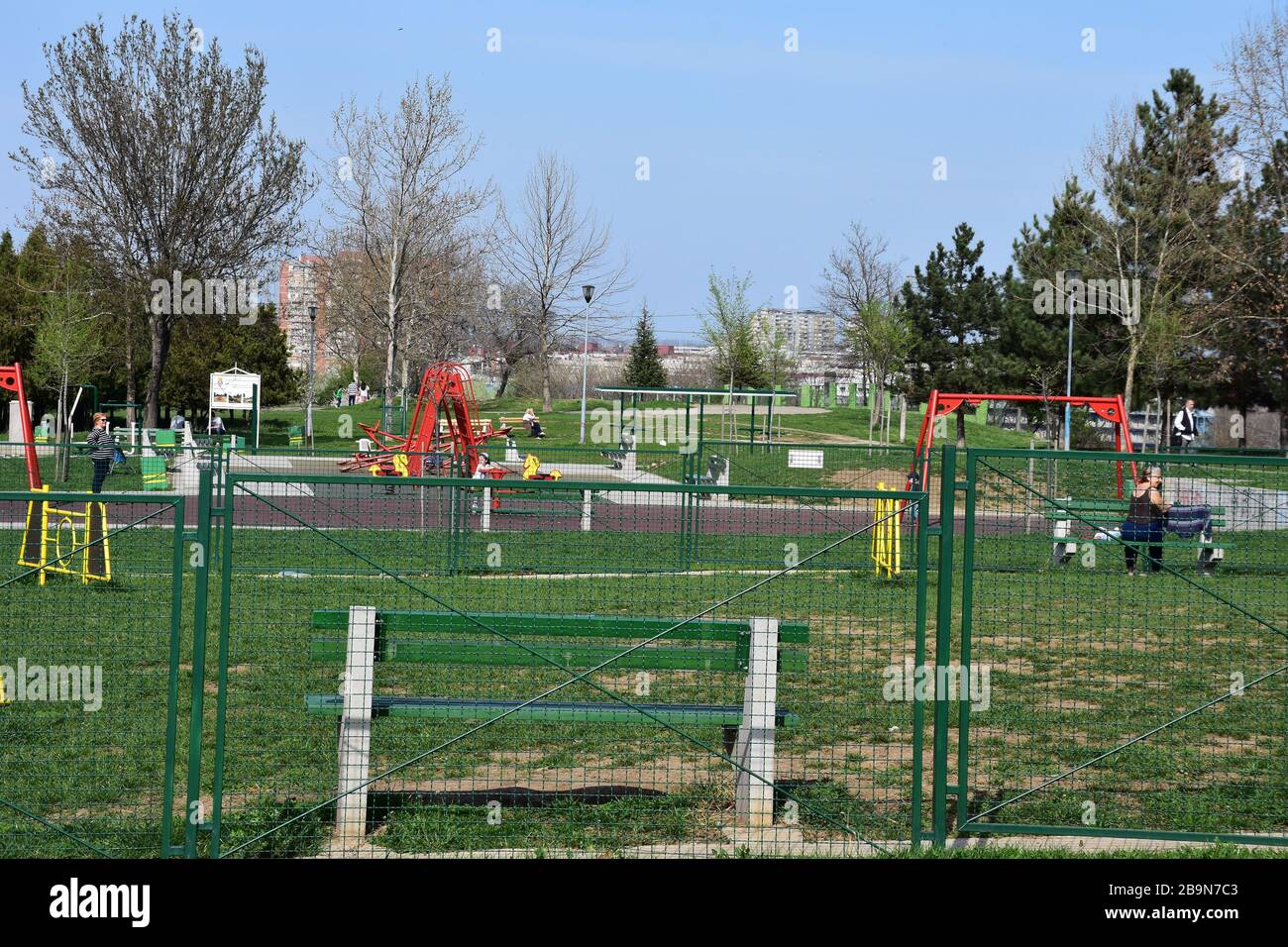 Recinto di metallo verde. C'è una panca verde dietro la recinzione. Nel parco sono presenti elettrodomestici per bambini Foto Stock