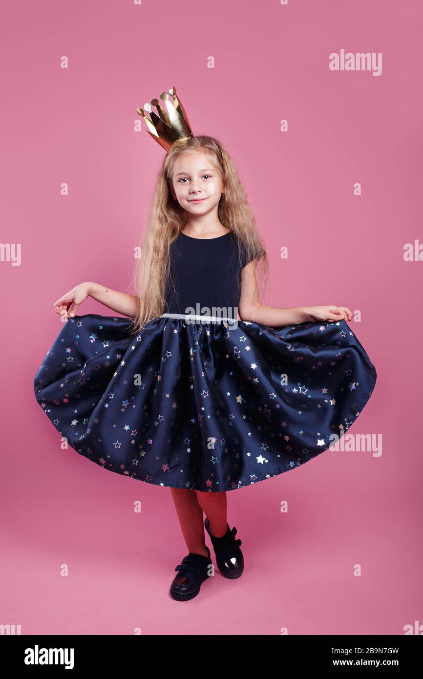 bella ragazza vestita come una piccola principessa su sfondo rosa Foto Stock