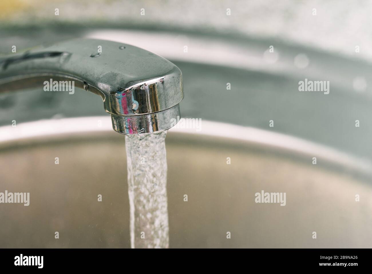 Aprite l'acqua del rubinetto dal rubinetto. L'acqua fluisce da un rubinetto cromato al lavandino. Spazio di copia Foto Stock