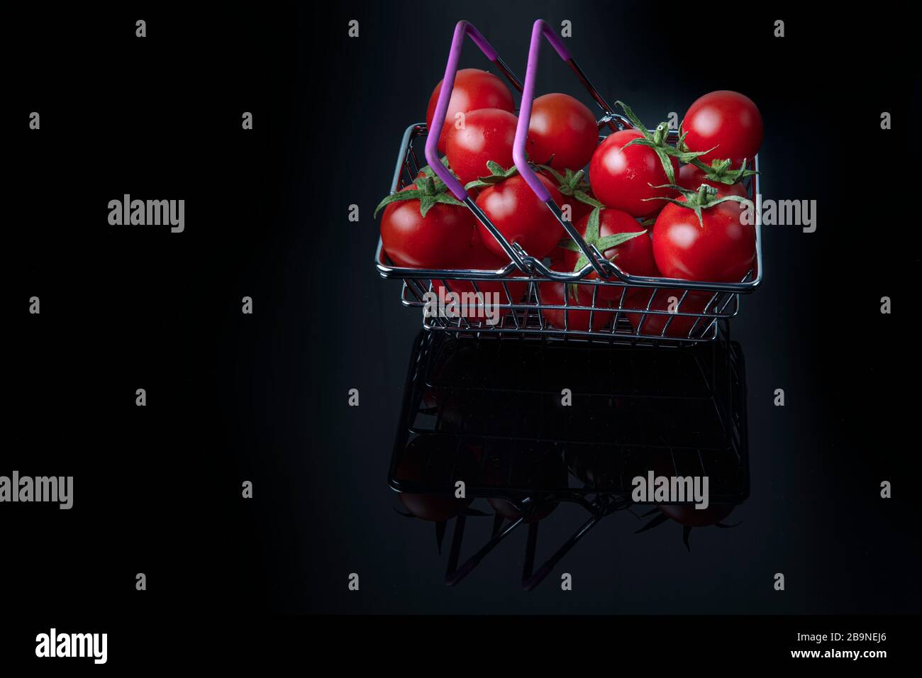 Concetto di supermercato. Primo piano con pomodori freschi. Carrello. Negozio di alimentari. Consegna di pomodori. Vendita al dettaglio e vendita. Pomodori ciliegini. Foto Stock