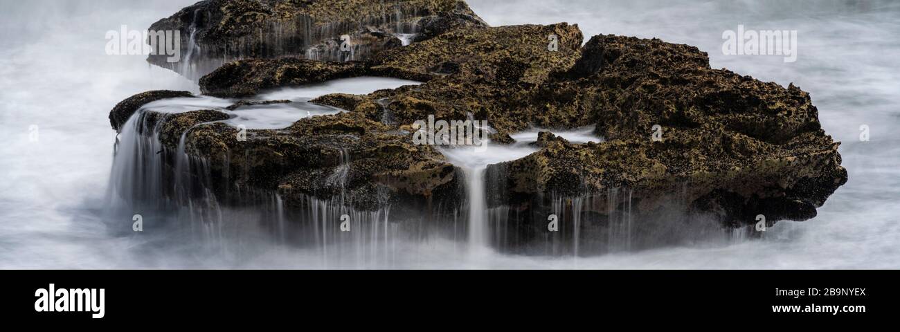 Roccia coperta in acqua di mare dopo un'onda cullata su di esso a rocce di Pancake, Nuova Zelanda. Punakaiki è una piccola comunità sulla costa occidentale dell'Isla meridionale Foto Stock