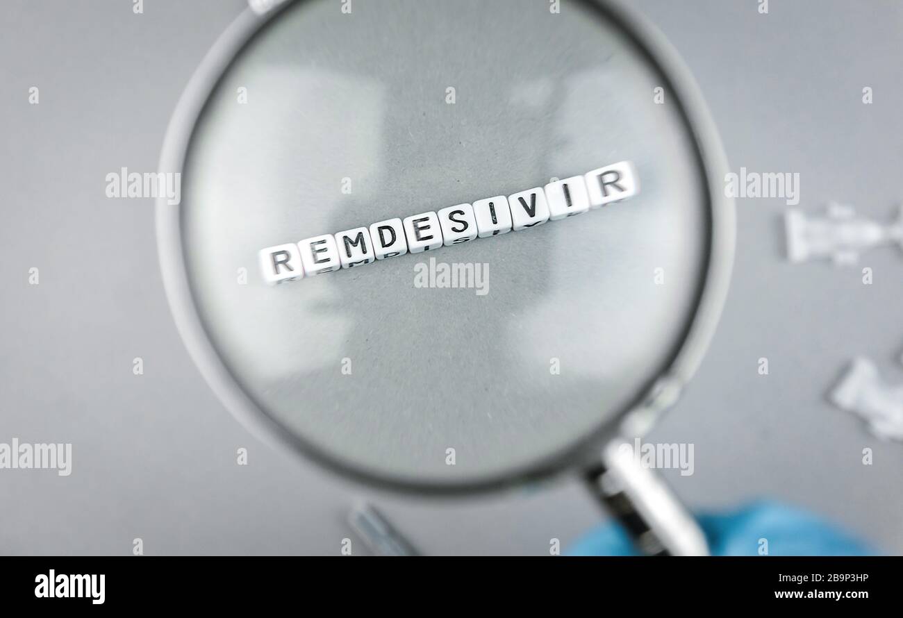 SARS cov 2 Covid 19 lente di ingrandimento su diciture alfabetiche con la parola Remdesivir un possibile trattamento per il virus Corona Foto Stock