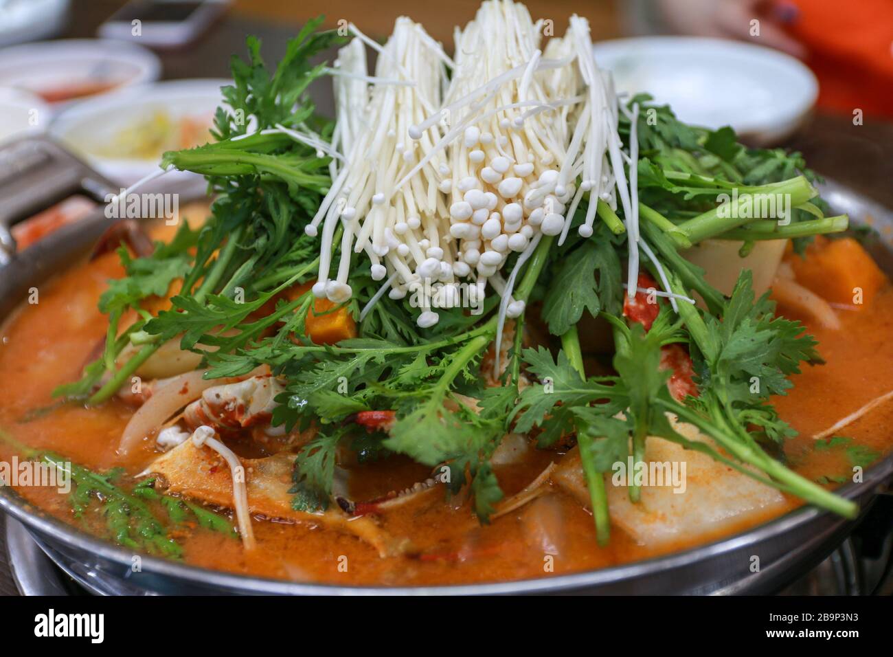 Cucina tradizionale coreana zuppa di granchio piccante con funghi enoki e verdure su un grande piatto Foto Stock