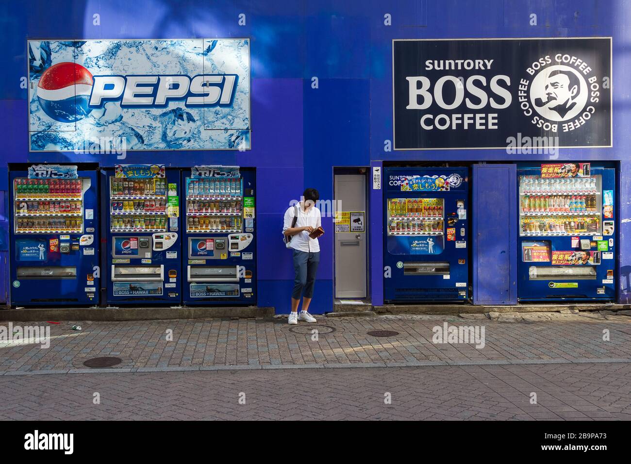 Un uomo controlla il suo portafoglio da alcuni distributori automatici a Center Gai, Shibuya, Tokyo, Giappone Foto Stock