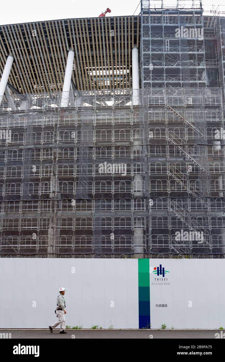 Un operaio cammina di fronte al cantiere per il nuovo stadio principale delle Olimpiadi di Tokyo del 2020 a Gaiemmae, Tokyo, Giappone Foto Stock