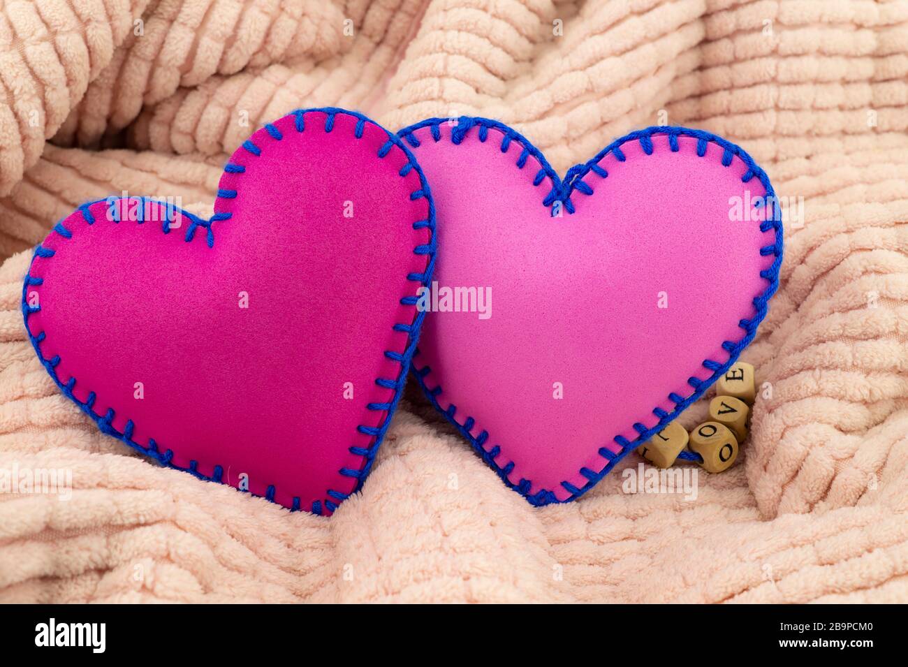 Mano cucito foglio di schiuma giocattolo cuori su uno sfondo rosa per romantico, relazione, San Valentino, cuore rotto amore concetto Foto Stock