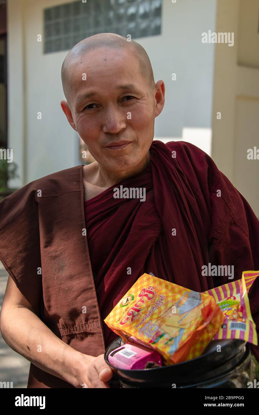 Amarapura, Myanmar - Gennaio 2020: Ritratto di un monaco buddista che trasporta le elemosine. Uomo saggio di fronte al monastero di Mahagandayone si ferma per posare per una foto Foto Stock