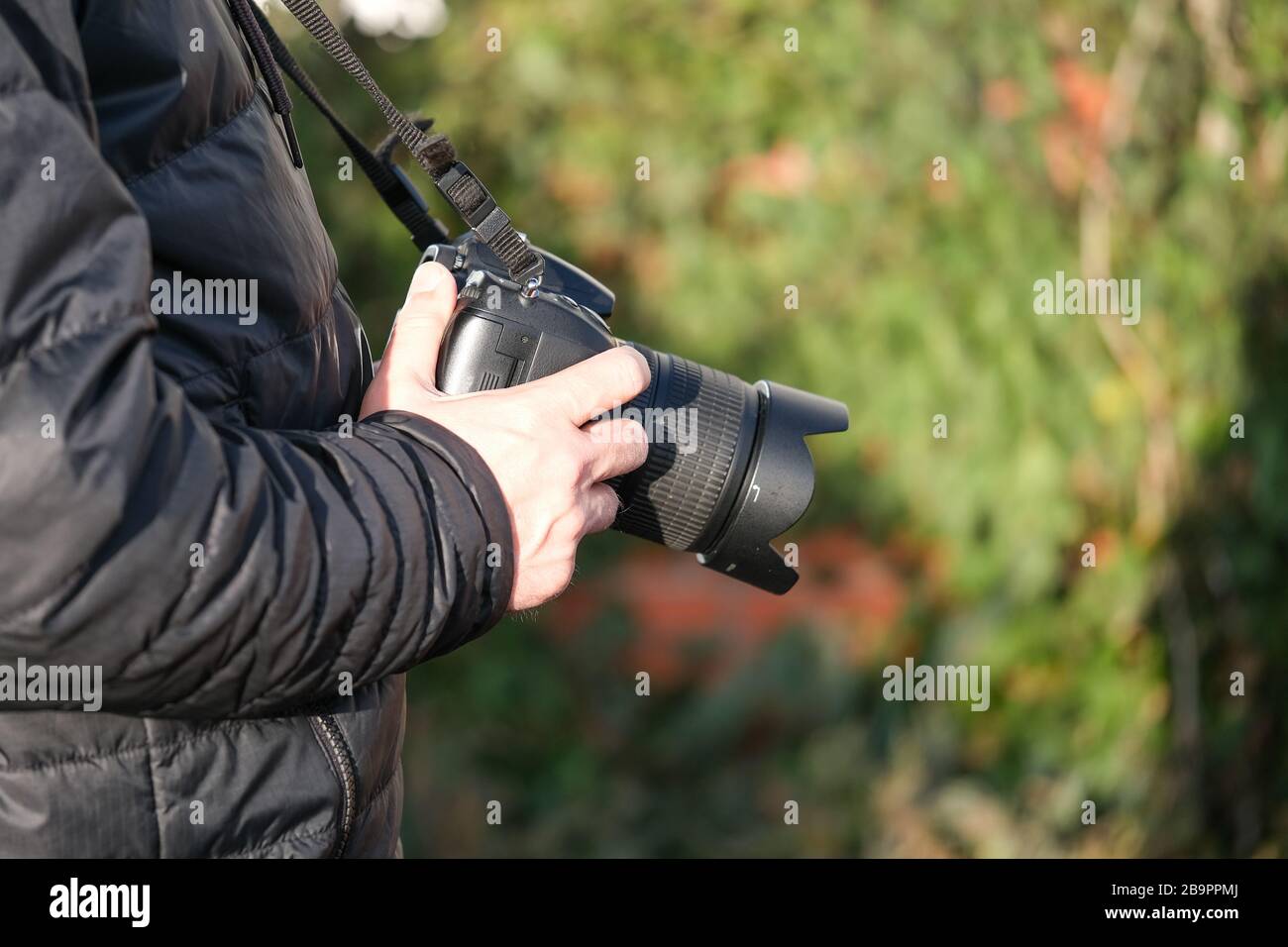 L'uomo fotografo con fotocamera dslr, all'aperto il giorno della primavera. Concetto hobby o fotografo professionista Foto Stock