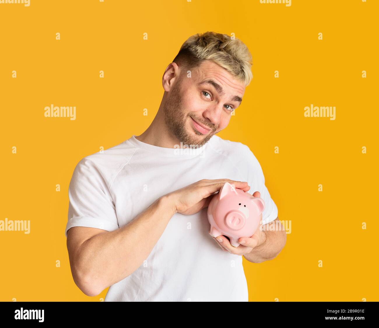 Concetto di accumulo di denaro. Uomo che accarezzava la banca dei piggy Foto Stock