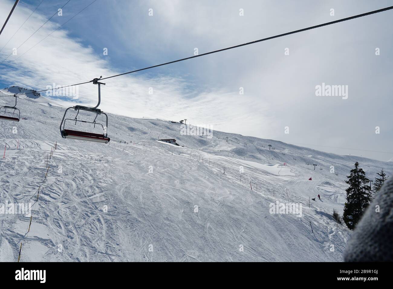 Seggiovie vuote in una stazione sciistica svizzera che si chiudono a causa del virus corona. Gli ultimi sciatori sono in pendenza. Il resort è più o meno abbandonato. Foto Stock