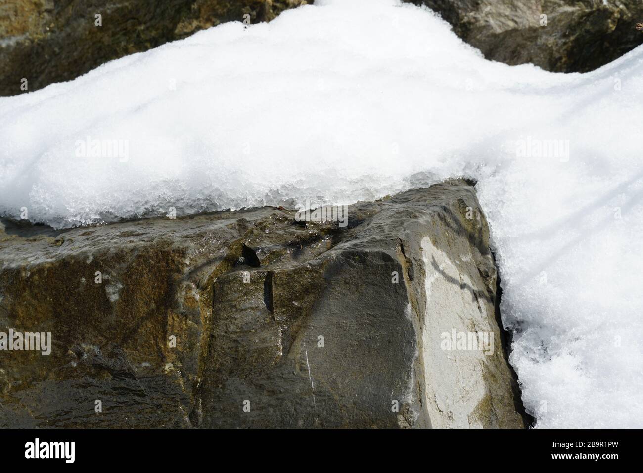 Uno strato di neve che si scioglie su una roccia in tempo di scongelamento. La roccia è bagnata, l'inverno sta per terminare. La primavera è in arrivo. Foto Stock