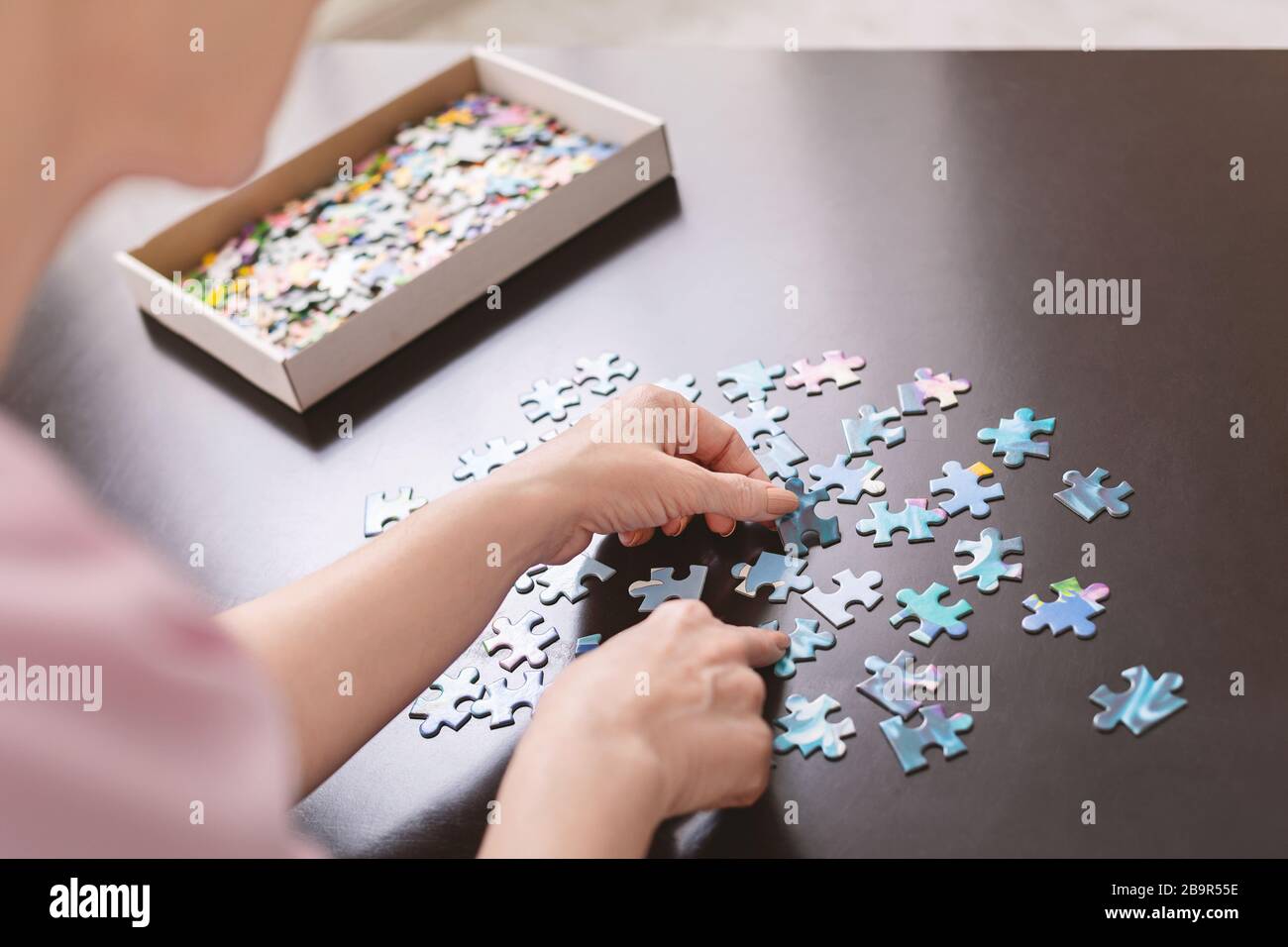 Auto-isolato signora senior giocare puzzle jigsaw a casa Foto Stock