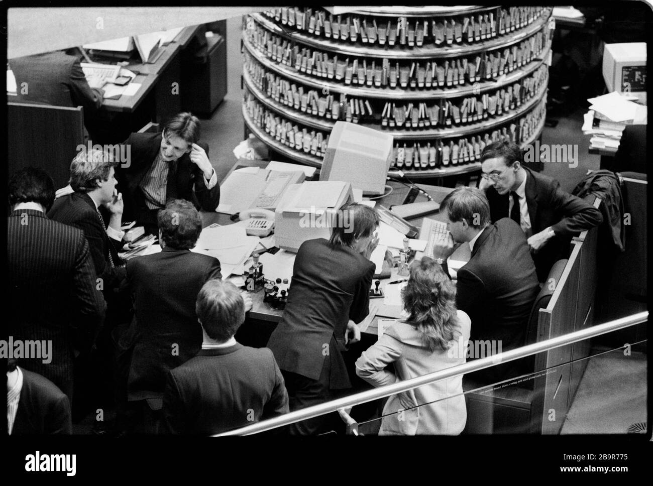 Città di Londra. Lloyd’s of London Insurance trading floor fotografato con permesso nel 1988. Lloyd's di Londra, generalmente conosciuta semplicemente come Lloyd's, è un mercato assicurativo e riassicurativo situato a Londra, Regno Unito. A differenza della maggior parte dei suoi concorrenti nel settore, non è una compagnia assicurativa; piuttosto, Lloyd's è un ente societario governato dal Lloyd's Act del 1871 e successivi atti del Parlamento. Opera come un mercato parzialmente mutualizzato all'interno del quale più finanziatori, raggruppati in gruppi, si riuniscono per raggruppare e diffondere il rischio. Questi underwriters, o 'membri ', sono un Foto Stock