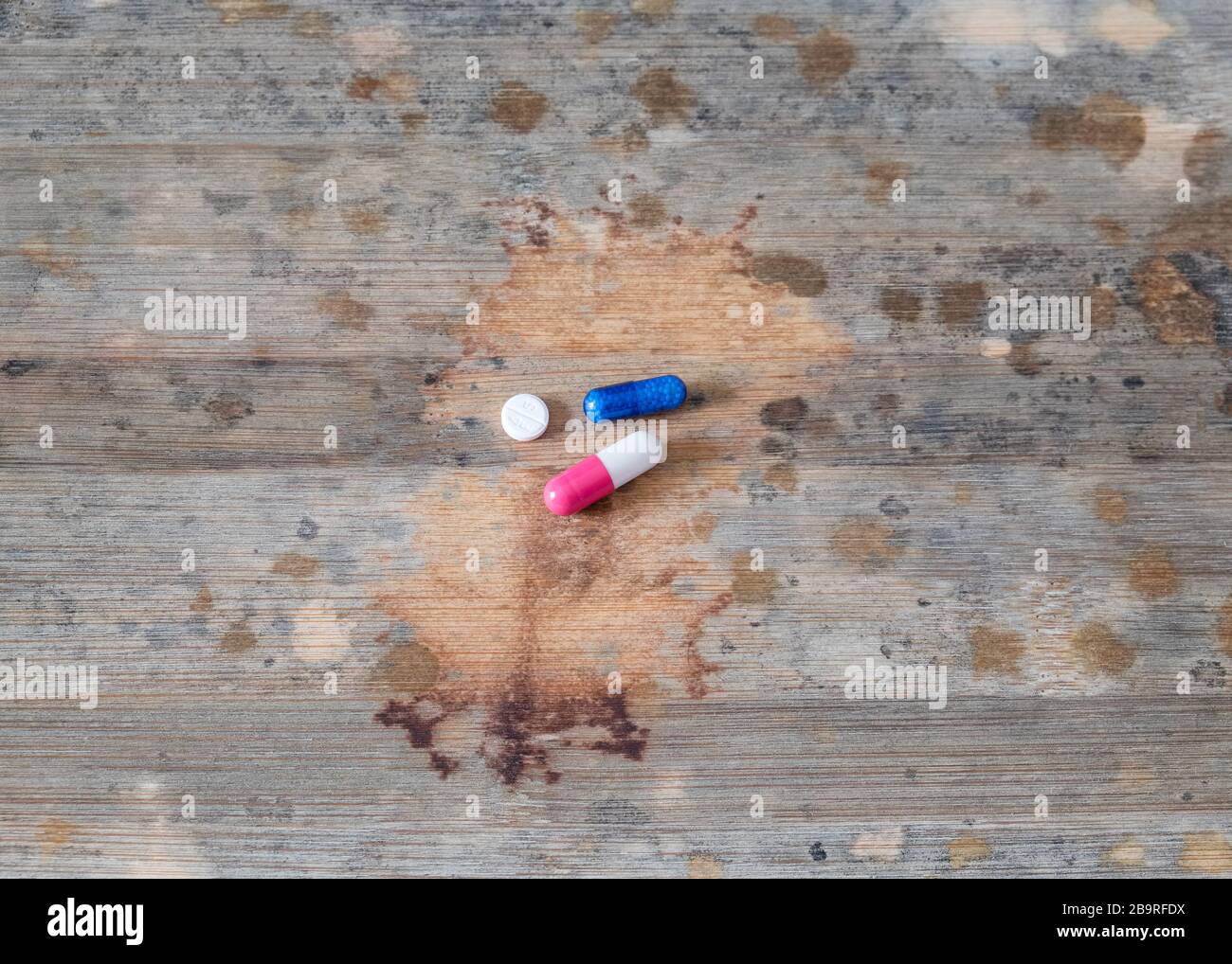 Concetto di assistenza medica, due capsule e una pillola al centro di un asse di legno con molti punti ricordare lo sviluppo di una malattia. Foto Stock