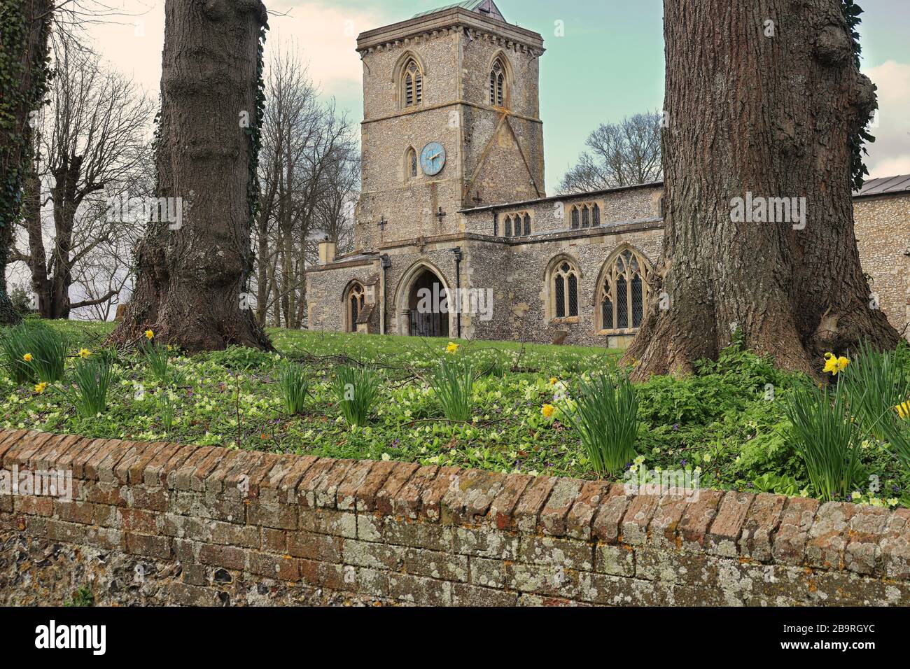 English Village Chiesa con Torre con tappeto di fiori primaverili nel cimitero Foto Stock