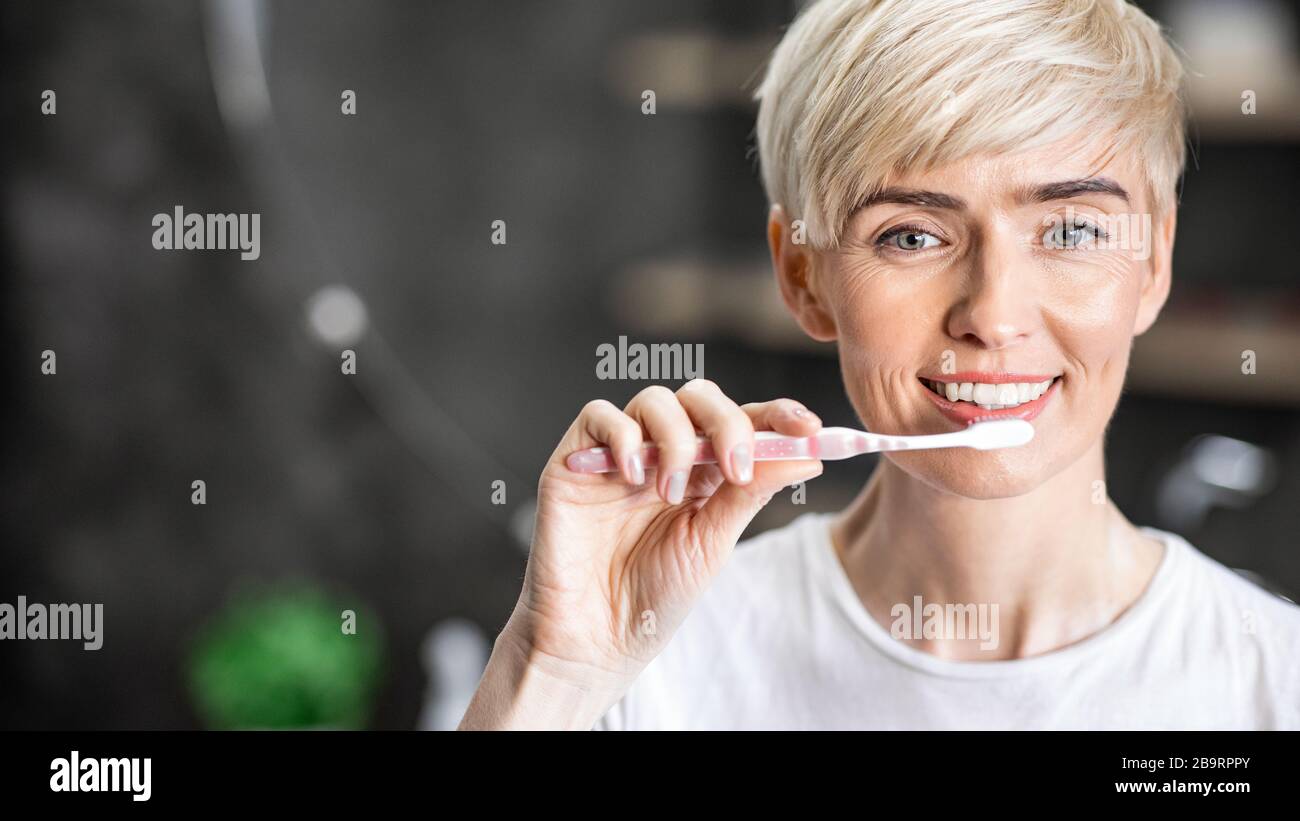 Ragazza allegra pulizia denti al mattino utilizzando spazzolino in bagno Foto Stock