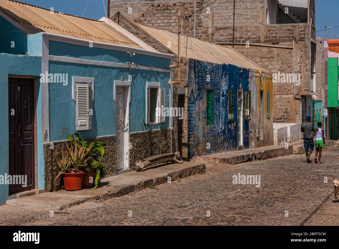 Strada con case dai colori esotici e una coppia di passaggio Foto Stock