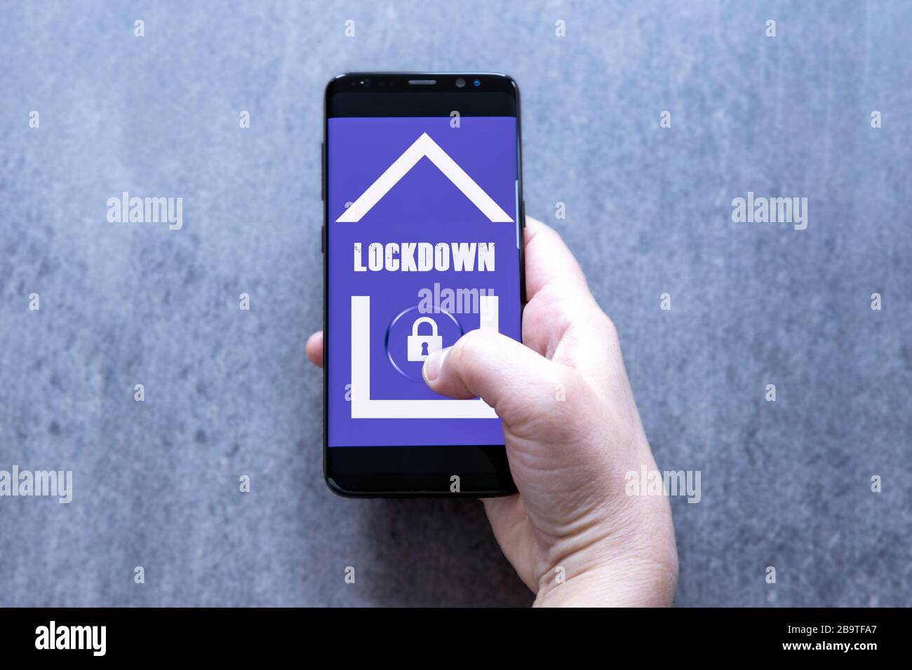 Dispositivo per la presa di mano femminile in quarantena Work from Home Concept con simbolo Home e Lock sul pulsante. Foto Stock